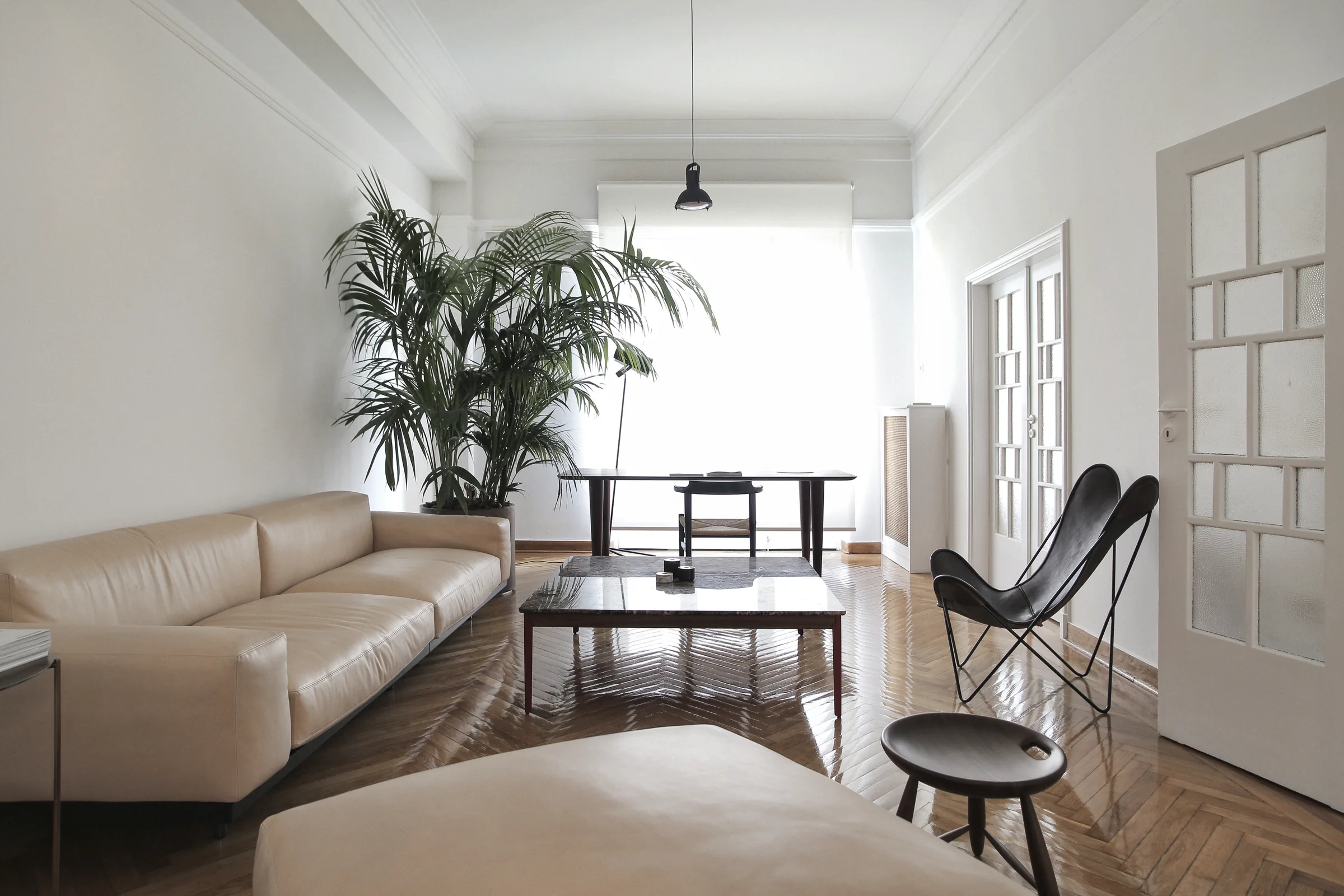 Bombyx showroom — Living room with pale seating, a black lounge chair and glazed doors